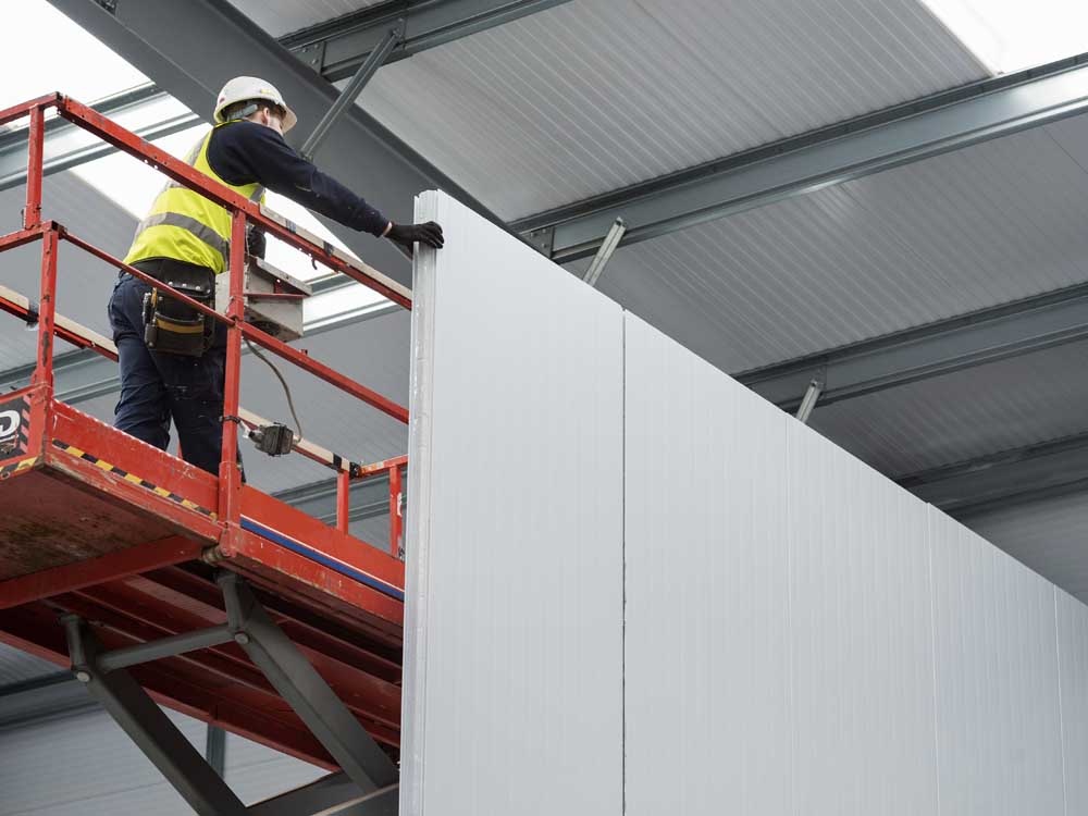 Cold Room constuction worker installing panels on a scissor lift